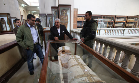 5 men stand arround a mummy coffin that had been looted.