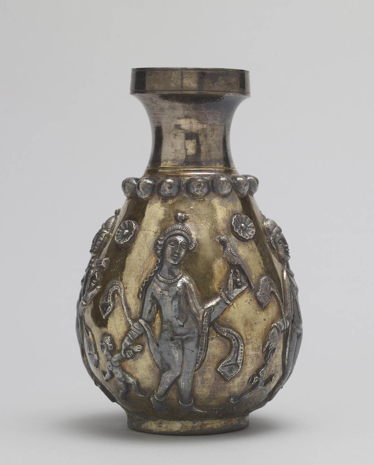 A bottle with sculptural figures of humans and animals, as well as floral details.